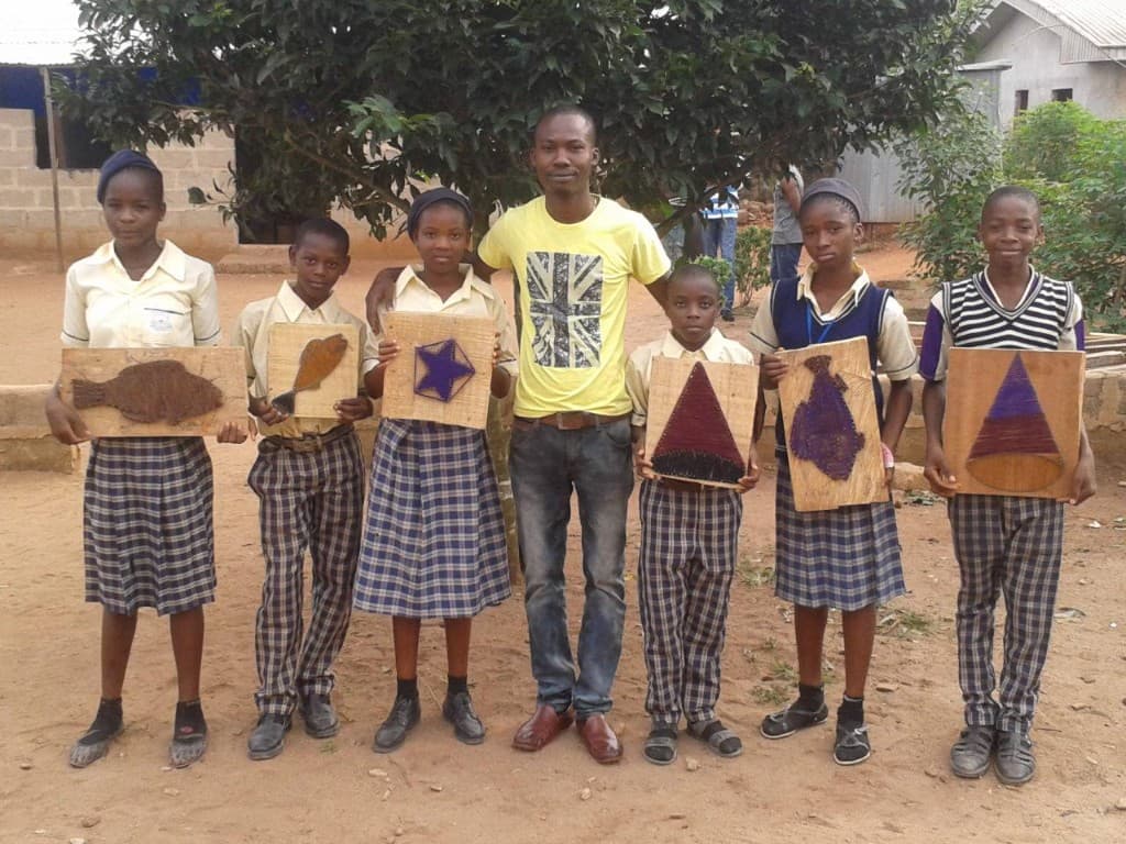 Students and a teacher presenting handmade string-art projects