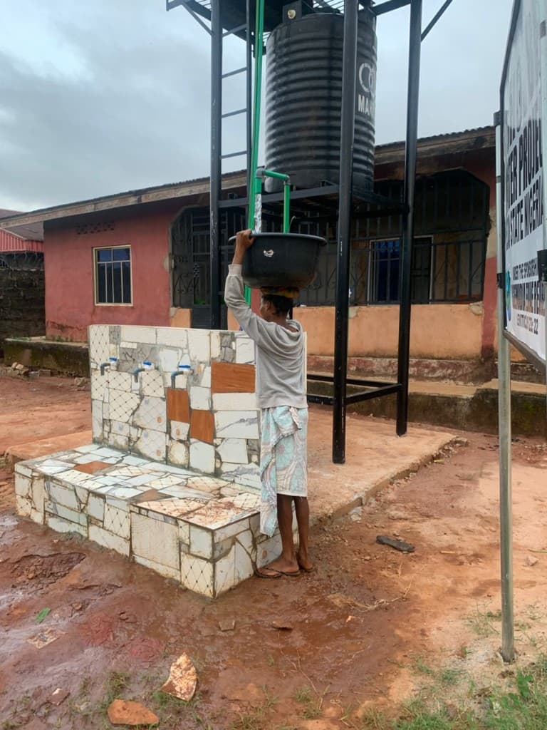 A resident collecting water from the elevated tank at the Ohovbe borehole